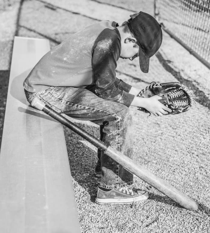 A young baseball player sitting alone